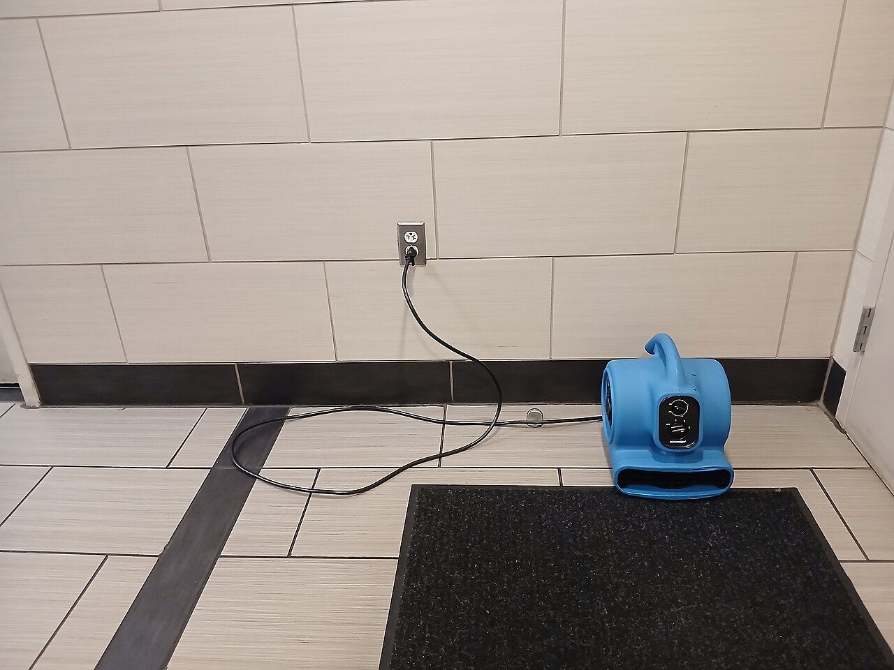 Real blue XPOWER blower plugged in and positioned on a tiled floor