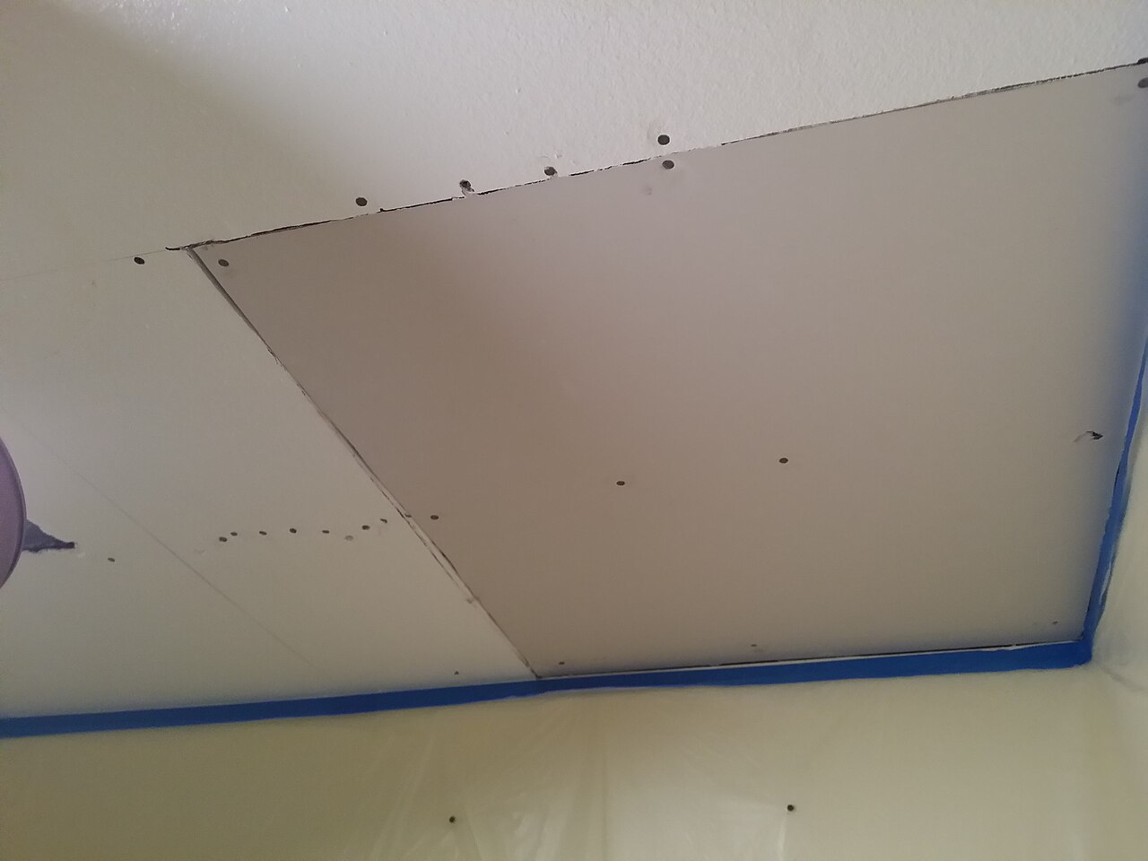 Photograph of a ceiling repair with taped edges after water damage